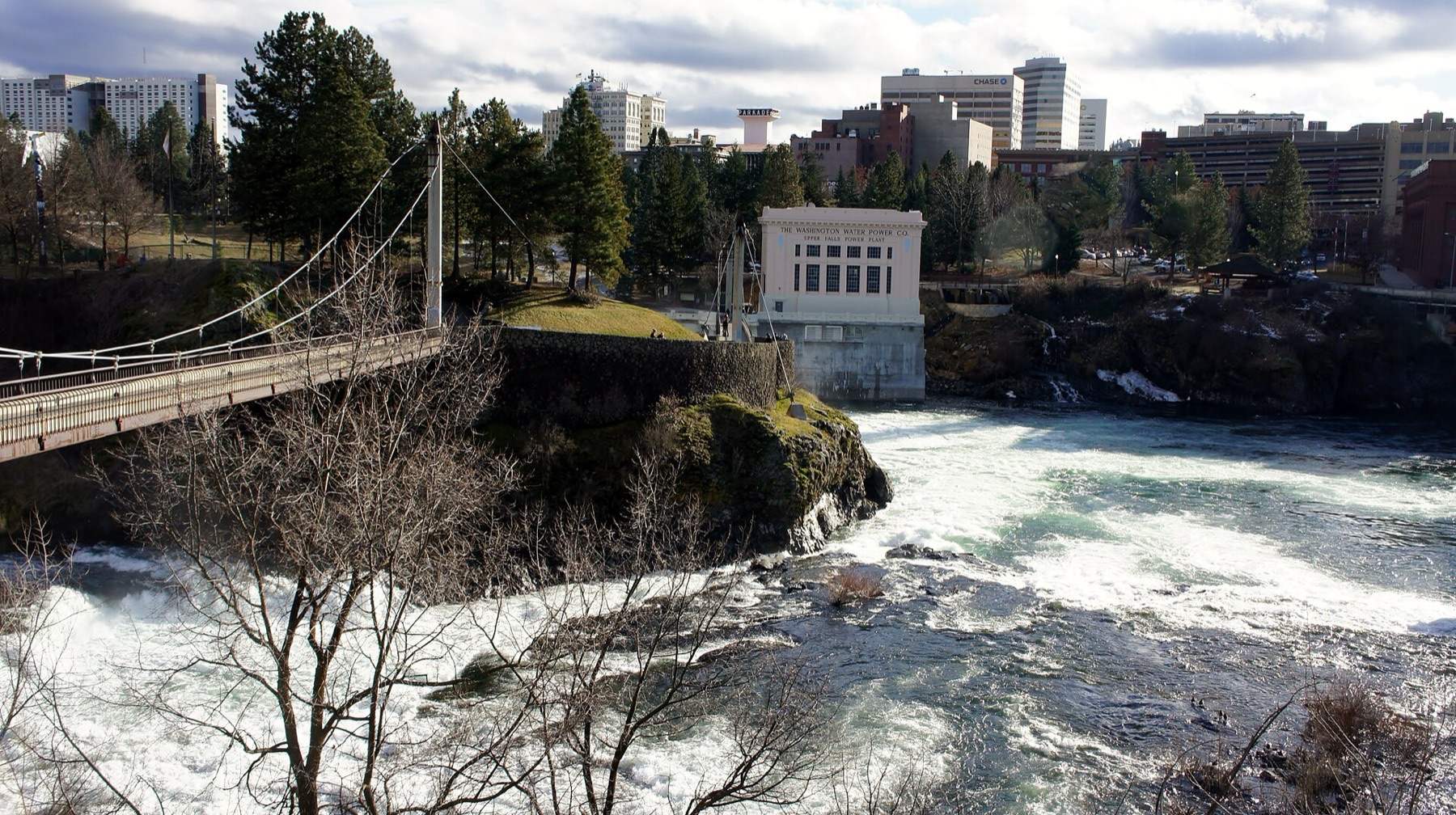 The Upper Spokane Falls, along with the Upper Falls Power Plant, and suspension bridge as seen in 2015 in Riverfront Park in Spokane, Washington