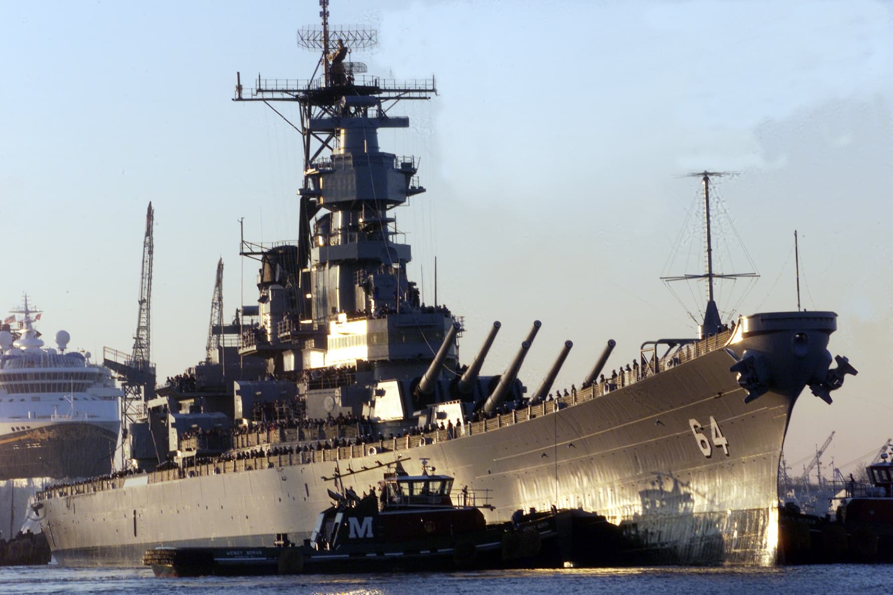 A tug boat nudges the bow of the battleship USS Wisconsin (BB 64) as the ship is pushed from the Norfolk Naval Shipyard to the Nauticus Museum in Norfolk, Va., on Dec